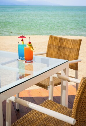 A glass table with two drinks, a wicker chair, and a view of the sea. - Ocean Breeze Puerto Vallarta (Puerto Vallarta)