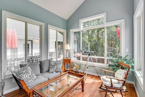 A living room with a sofa, rocking chair, and a glass coffee table.