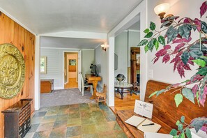A wooden interior with a tiled floor, a wooden bench, a desk with a laptop, and a wall-mounted light fixture.