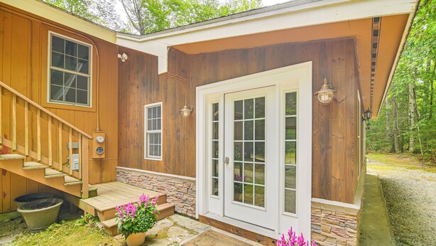 Ein Holzhaus mit einer Veranda, Steinstufen und einer Tür mit Glasfeldern.