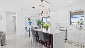 A modern kitchen with a central island, white cabinetry, and pendant lighting.
