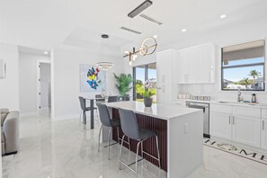 A modern kitchen with a central island, white cabinetry, and pendant lighting.