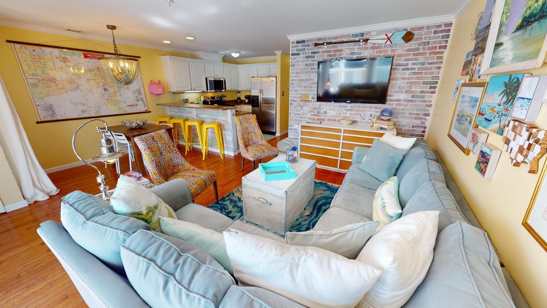 A living room with a sofa, chairs, a coffee table, and a TV mounted on a brick wall.