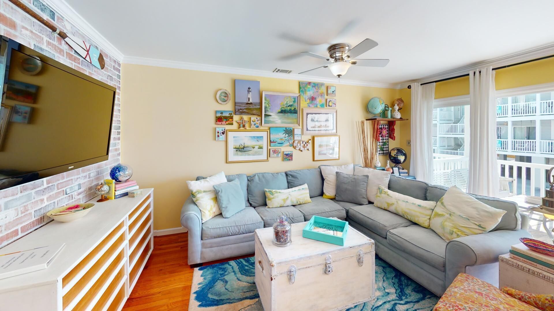 A cozy living room with a sectional sofa, a flat-screen TV, and a ceiling fan.