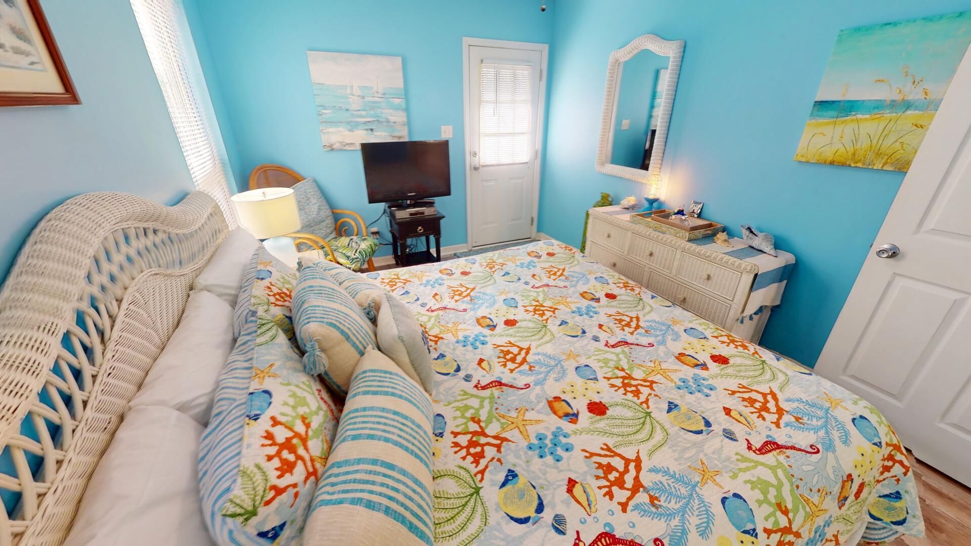 Una habitación con cama, televisor, cómoda y puerta.