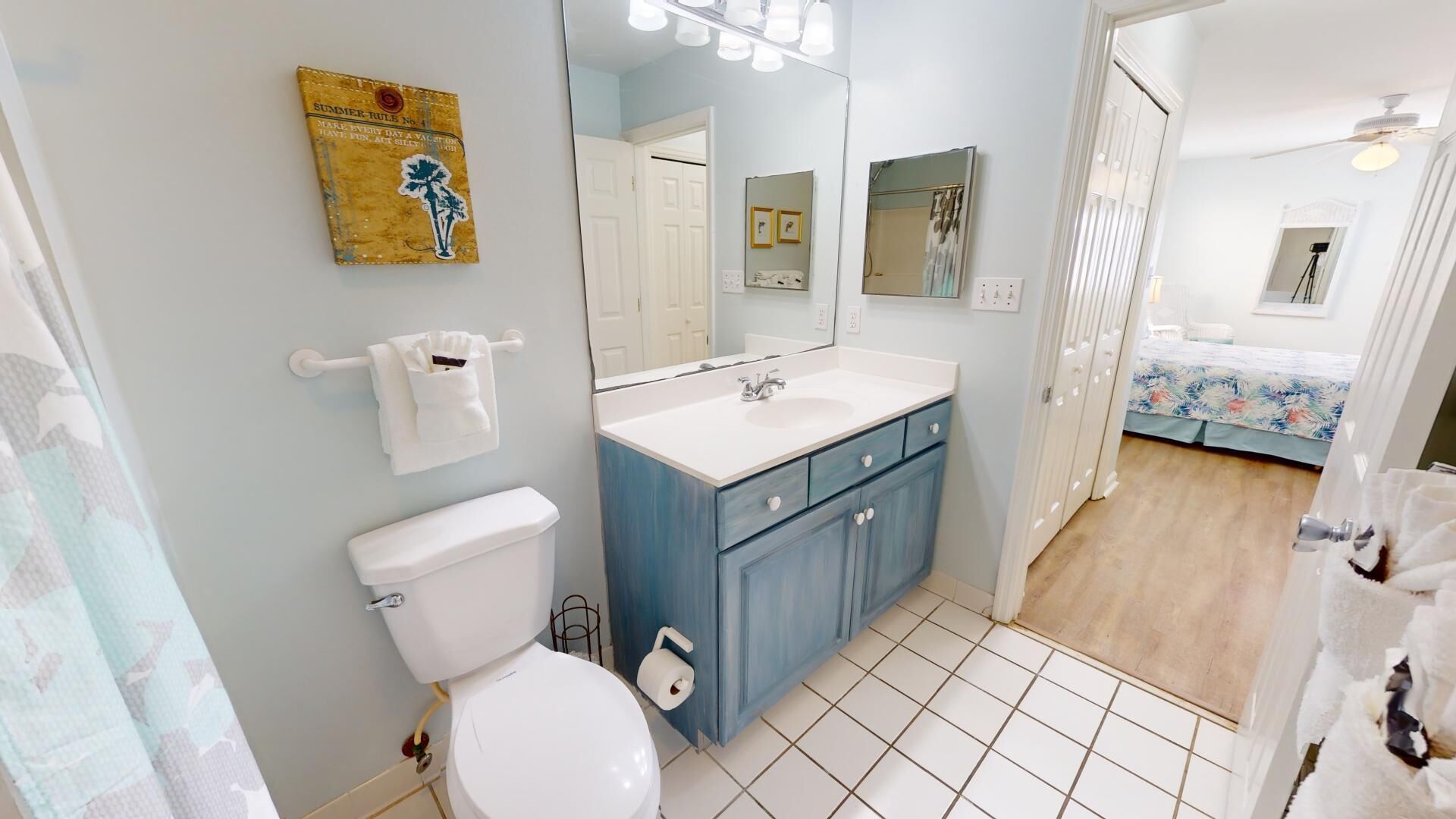 A bathroom with a toilet, sink, and cabinet, a mirror, and a shower curtain.