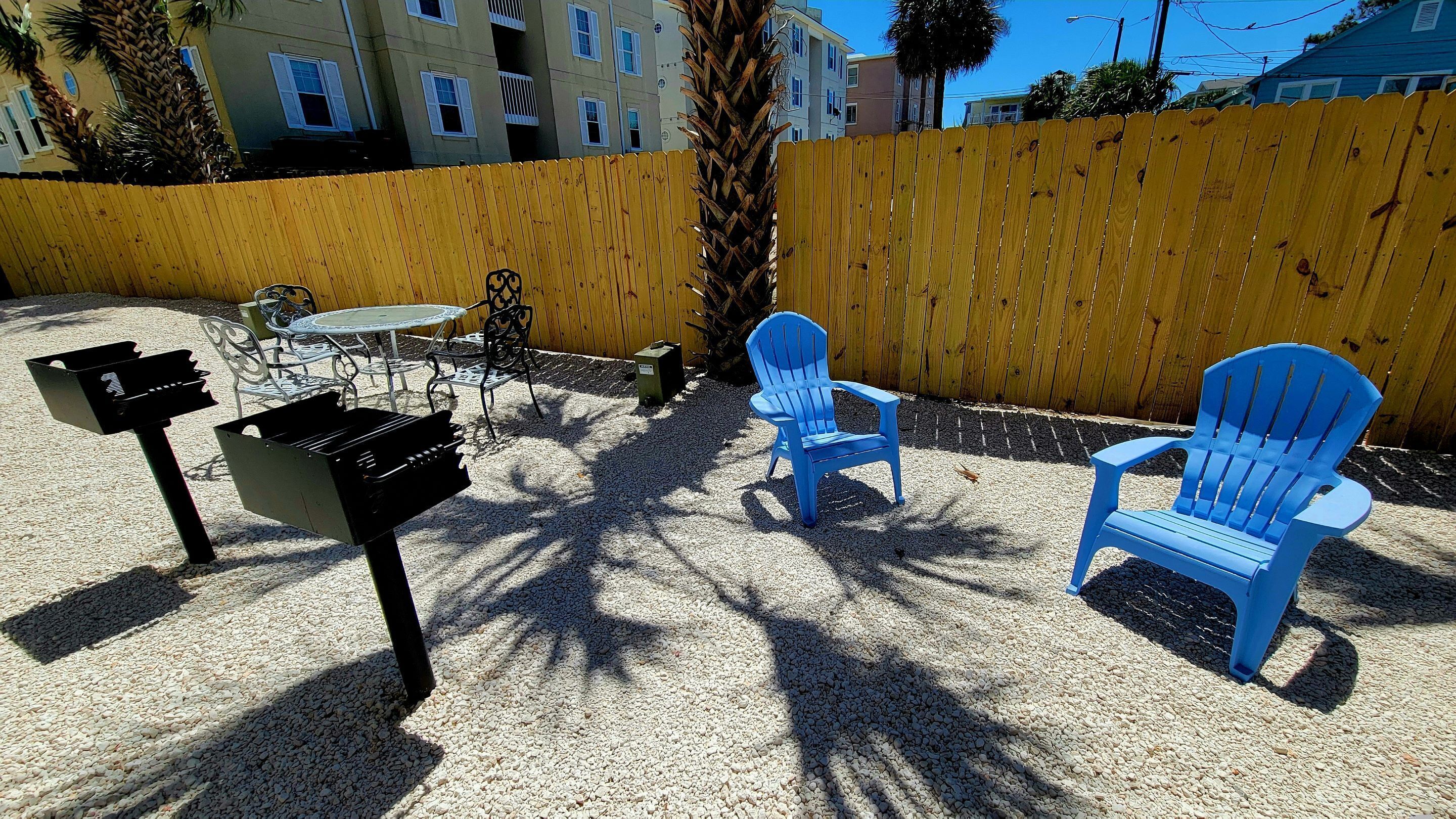 Une terrasse avec des meubles d’extérieur, un barbecue et une clôture en bois.
