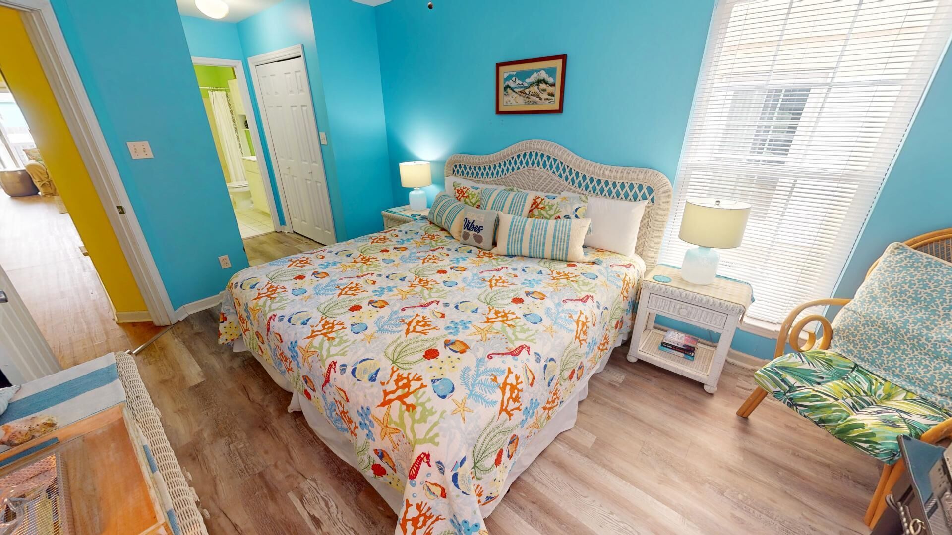 A bedroom with a bed, nightstands, a chair, a window with blinds, and a door.
