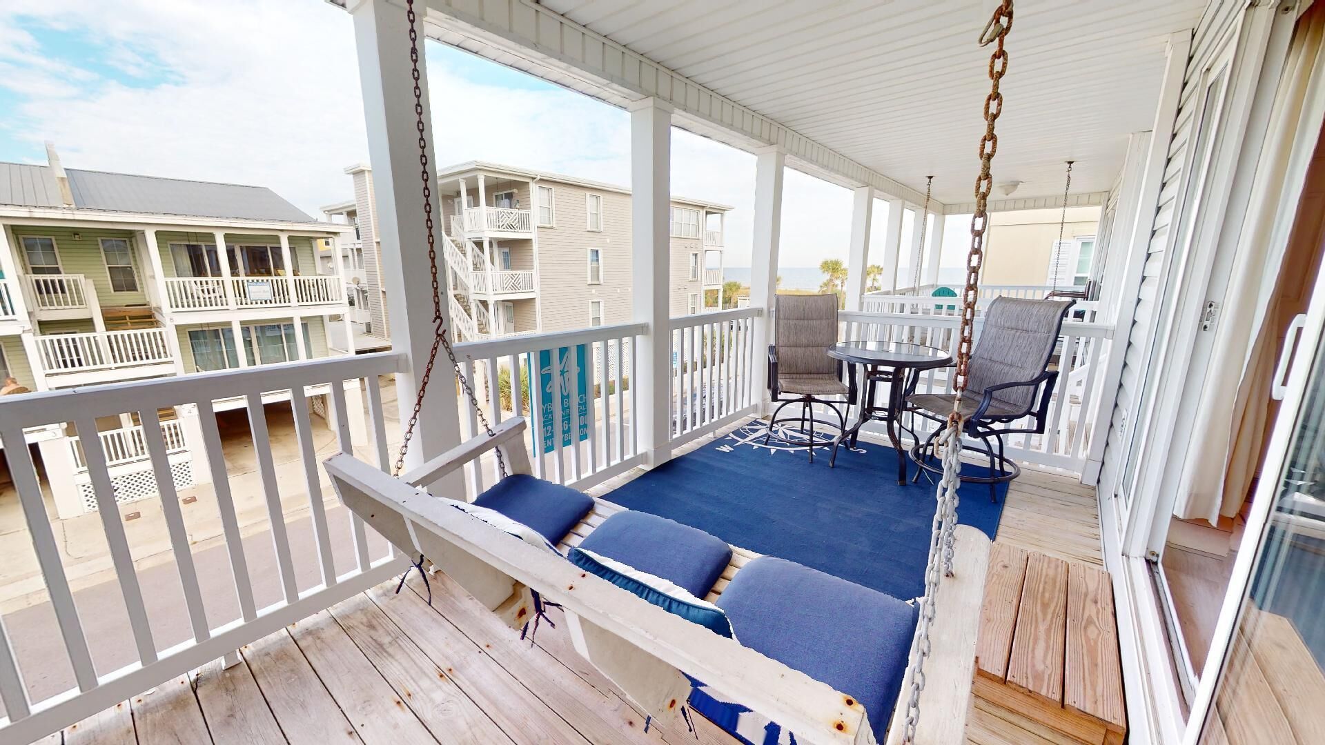 A covered outdoor area with a swing, seating, and a table.