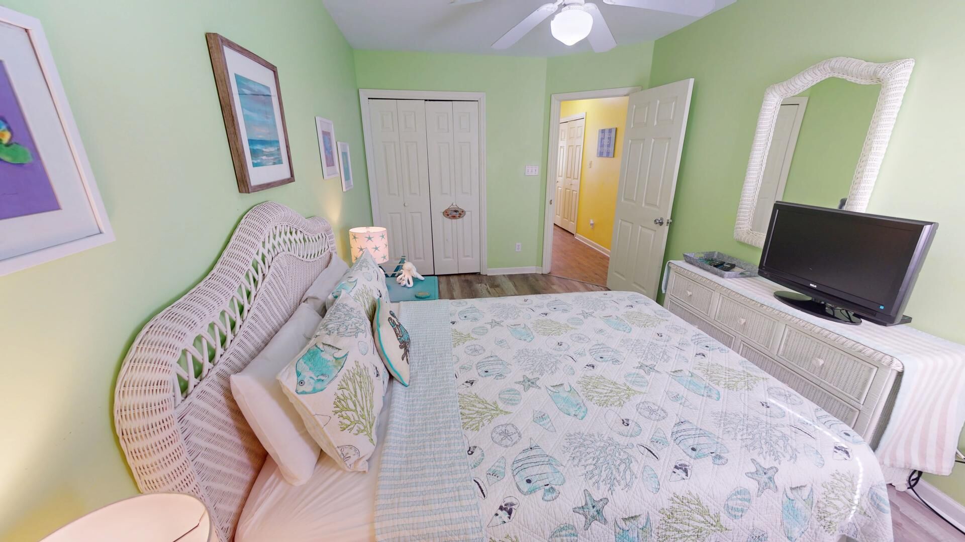 A bedroom with a bed, a television, a dresser, and a door leading to another room.
