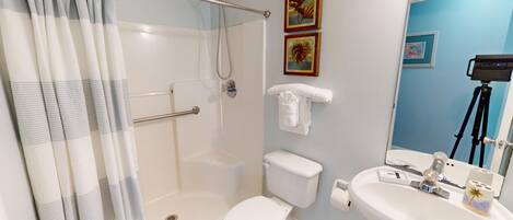 A bathroom with a shower, toilet, and sink.