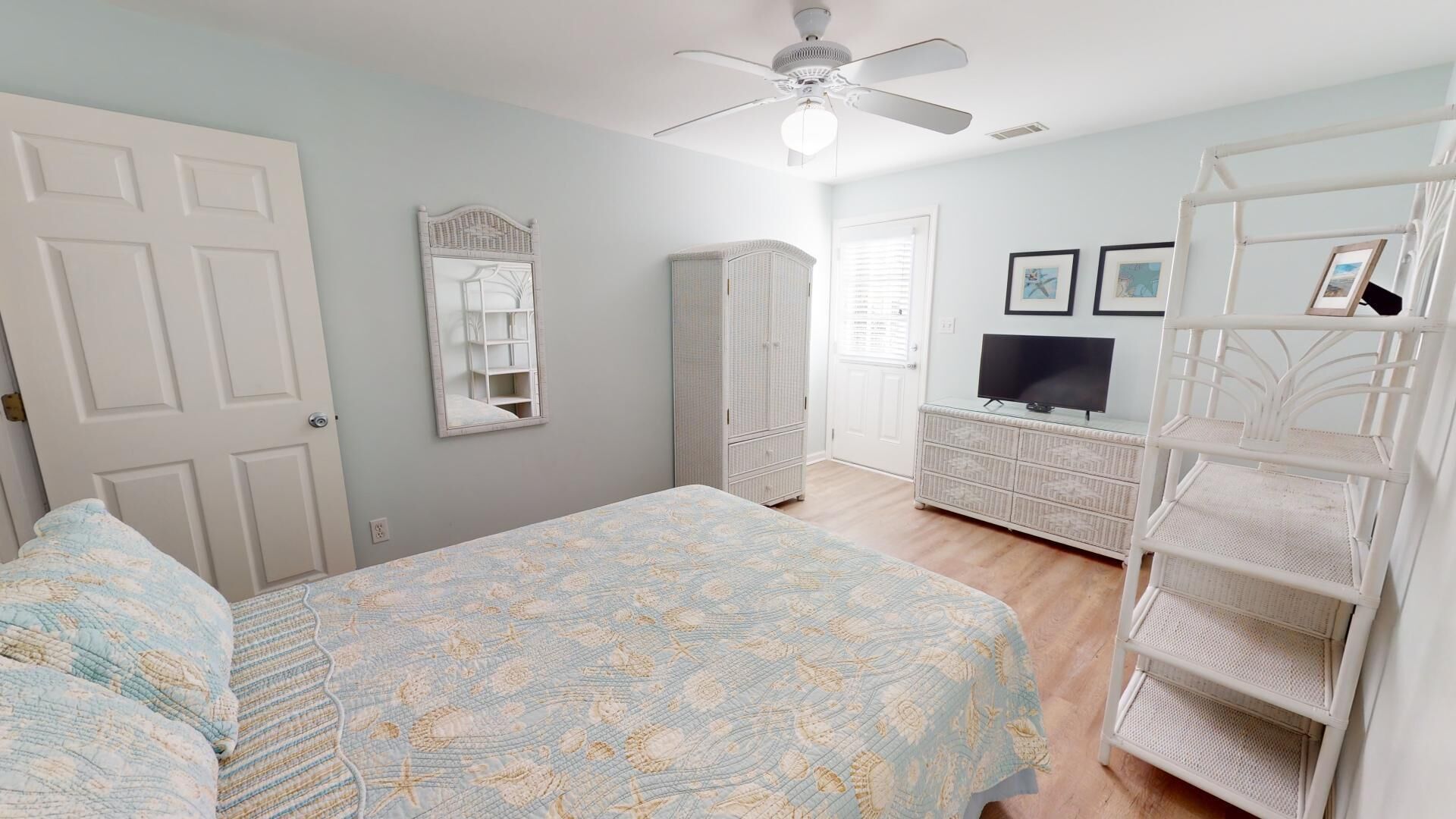 A bedroom with a bed, a wardrobe, a TV, and a ceiling fan.