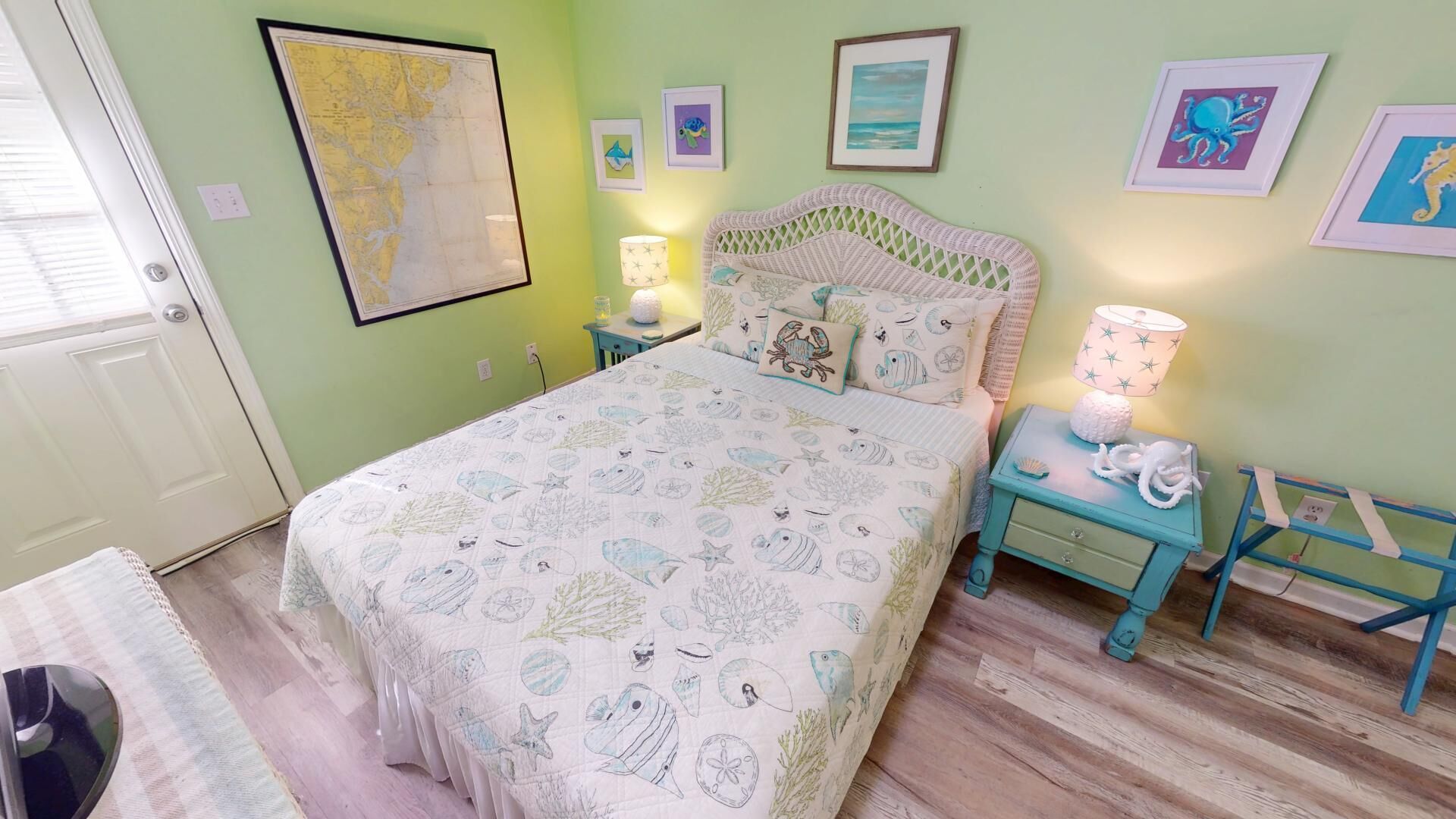 A bedroom with a bed, nightstands, a map on the wall, and framed pictures.