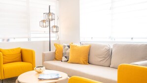 Una sala de estar moderna con un sofá, dos sillones amarillos, una mesita de centro y una lámpara de pie.
