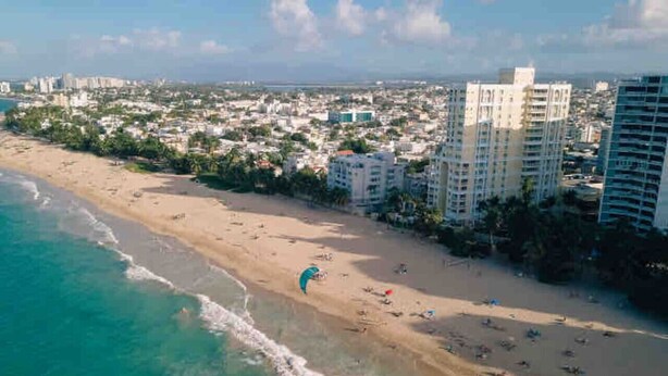 Un paisaje urbano costero con playa, rascacielos y cielo despejado.