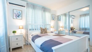 Un dormitorio moderno con una cama grande, mesitas de noche con lámparas, un espejo y obras de arte en las paredes.
