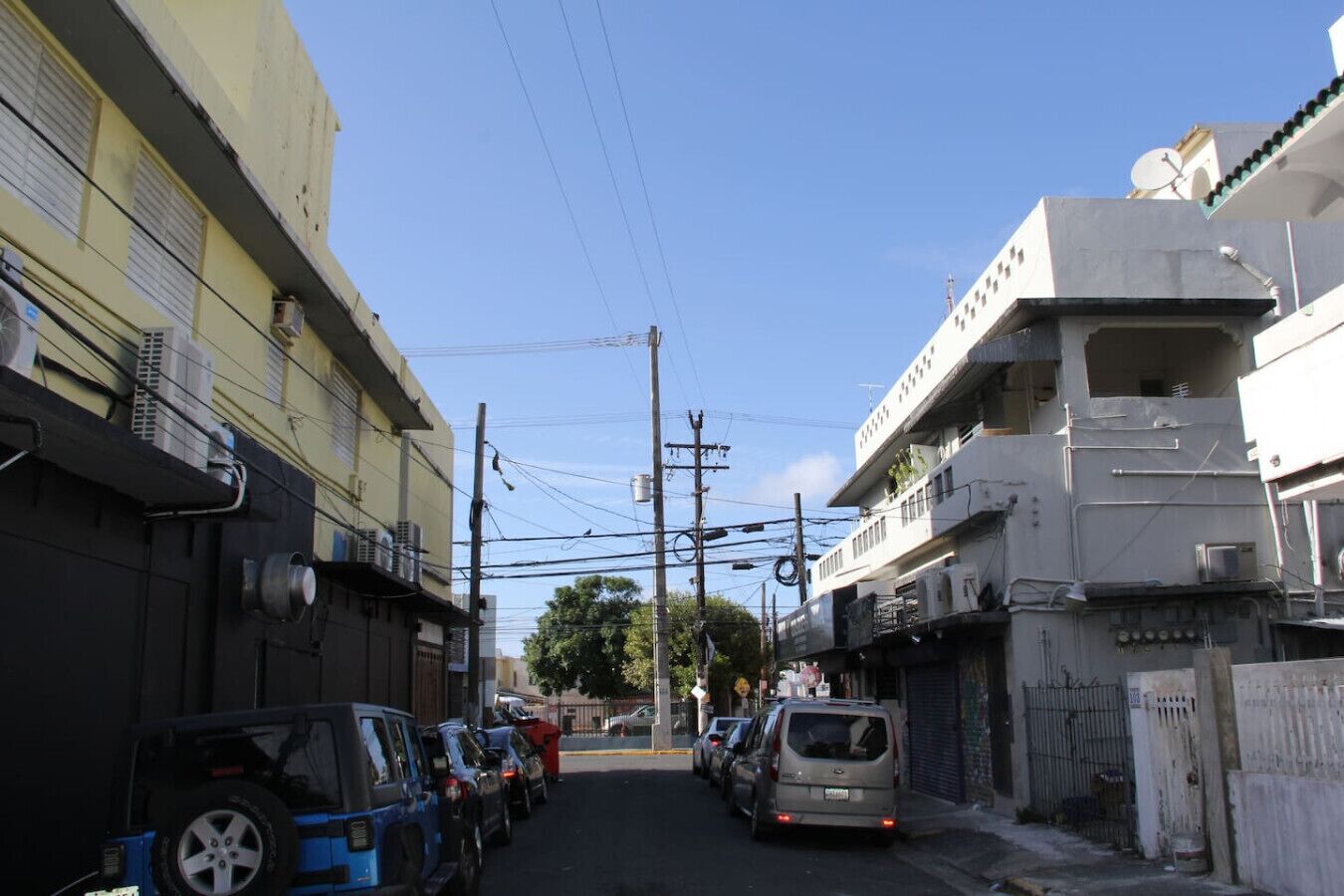 Une rue étroite en ville, bordée de voitures garées et d’immeubles.