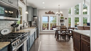 A kitchen with a stove, cabinets, and a dining area with chairs and a table.