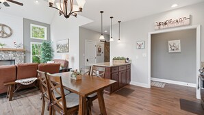 A spacious living area with a wooden dining table, a sofa, and a fireplace.