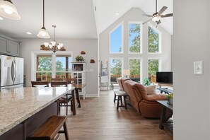 A spacious kitchen with a large island, wooden flooring, and a view of the outdoors through large windows. - Mountain Escape with Hot Tub | Game Room | Trails (Ellijay)
