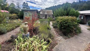 A rustic garden with a stone pathway leading to a wooden cottage.