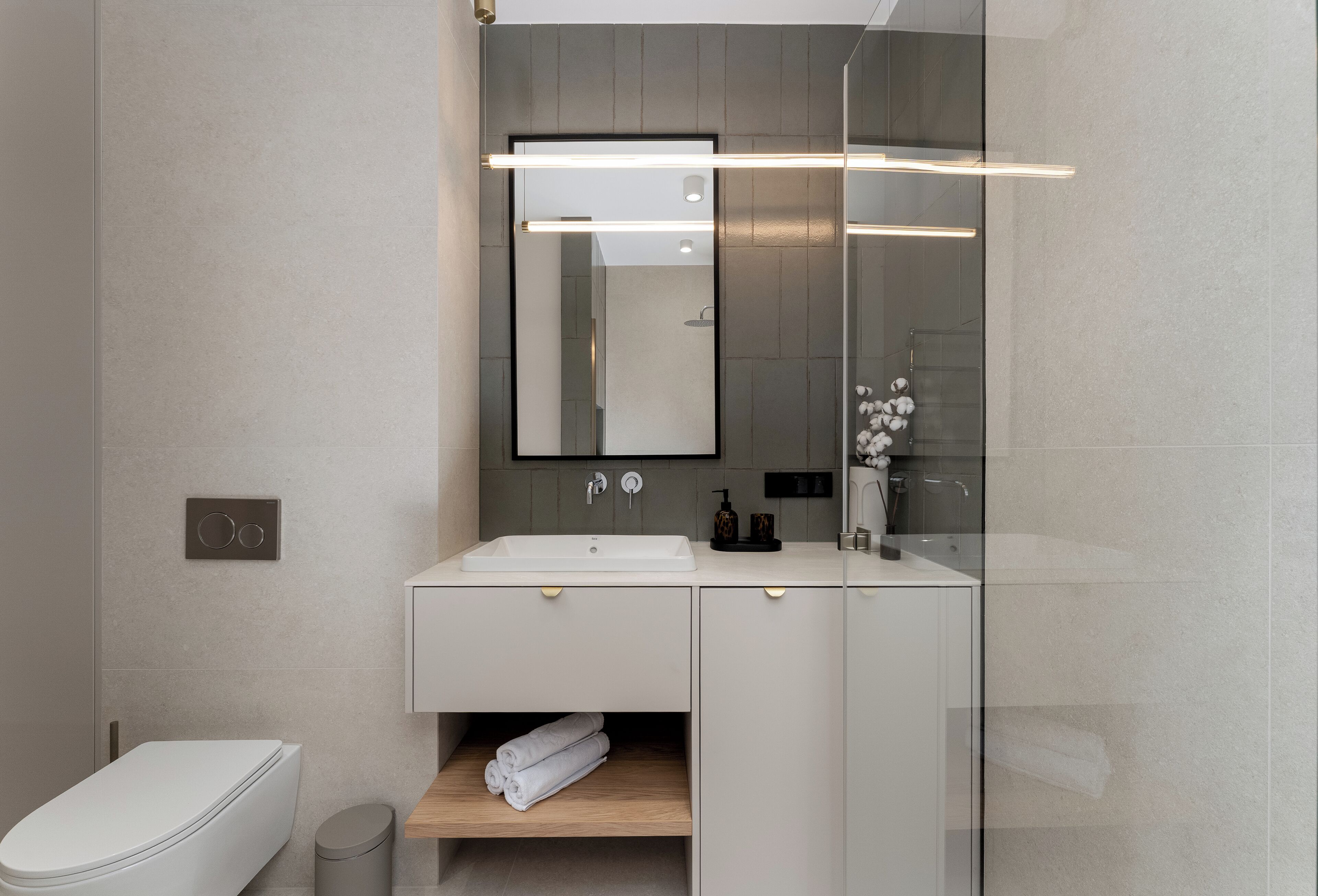 Un baño moderno con un inodoro blanco, un lavamanos con un espejo encima y un estante para toallas.