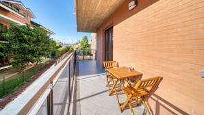 A balcony with a wooden table and chairs, a brick wall, and a view of the street. - SGHouse apartment with free parking (Rivoli)