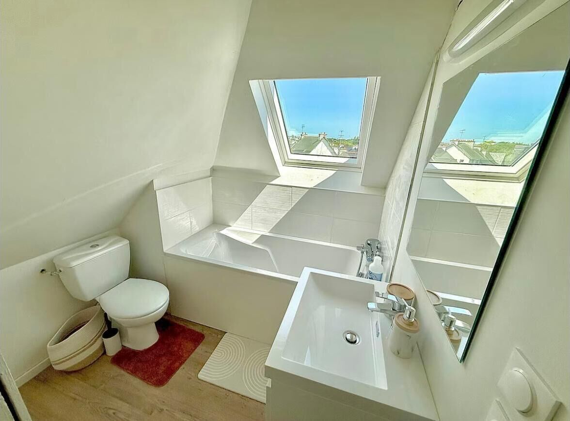 Une salle de bain moderne dotée d’une lucarne, d’une baignoire, de toilettes et d’un lavabo.