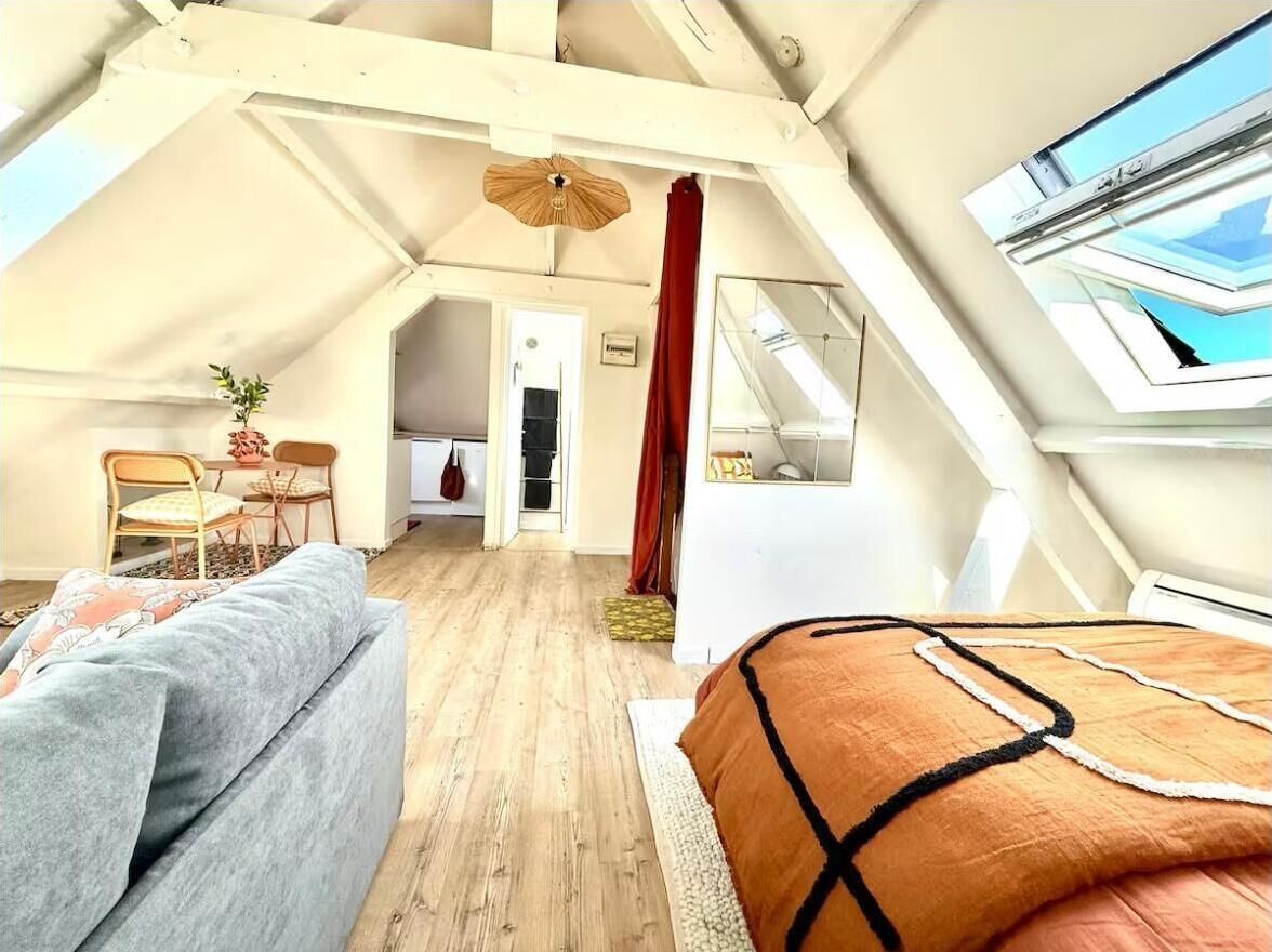 Una camera da letto mansardata accogliente con letto a soppalco, un divano, un tavolo da pranzo con sedie e un angolo cottura.