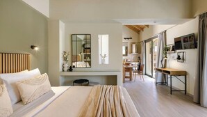 A modern bedroom with a large bed, a desk, and a mirror. There is a view of a kitchen and dining area in the background.