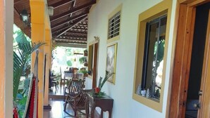 A corridor with tiled flooring, wooden chairs, a hammock, and a door leading to a room. - RELAX IN WARM ROOMS AND SPACE TO REST COMFORTABLY. (León)
