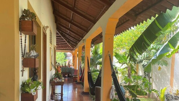 A covered walkway with tiled flooring, wooden pillars, and hanging plants. - RELAX IN WARM ROOMS AND SPACE TO REST COMFORTABLY. (León)