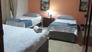 A hotel room with two beds, a small table, a lamp, and a painting on the wall. - RELAX IN WARM ROOMS AND SPACE TO REST COMFORTABLY. (León)