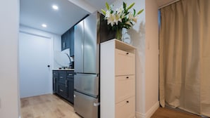 A modern kitchen with a stainless steel refrigerator, dark cabinets, and a white storage unit. - Spacious Studio for 4 | Full Kitchen + Laundry (Montréal)