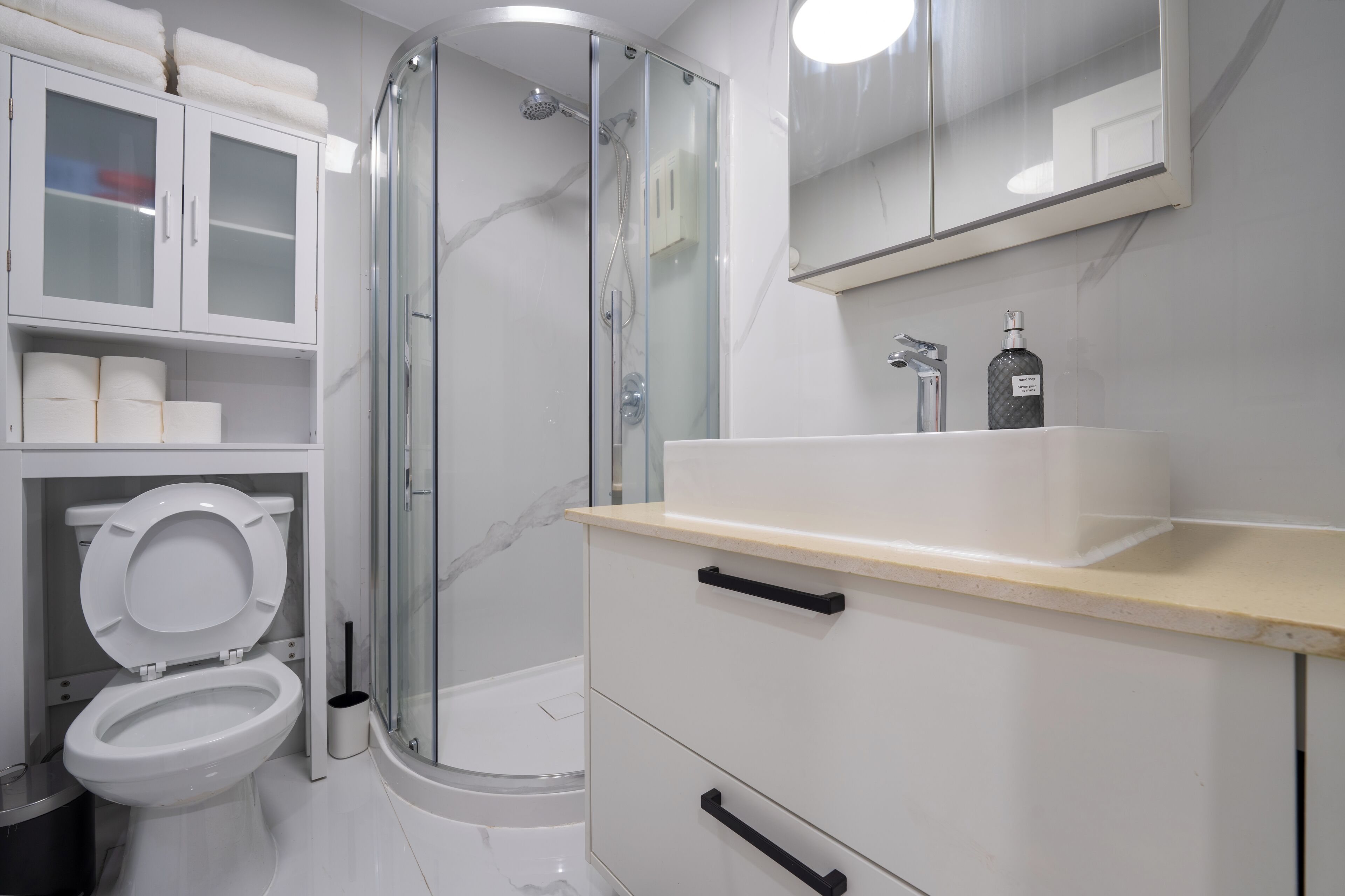Un baño moderno con ducha envuelta en vidrio, inodoro y tocador con espejo.