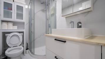Un baño moderno con ducha envuelta en vidrio, inodoro y tocador con espejo.