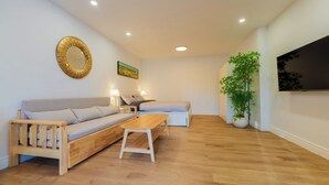 A modern living room with a sofa, a coffee table, and a TV. - Spacious Studio for 4 | Full Kitchen + Laundry (Montréal)