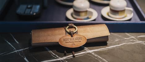 A leather-bound menu with a keychain attached, placed on a marble surface.
