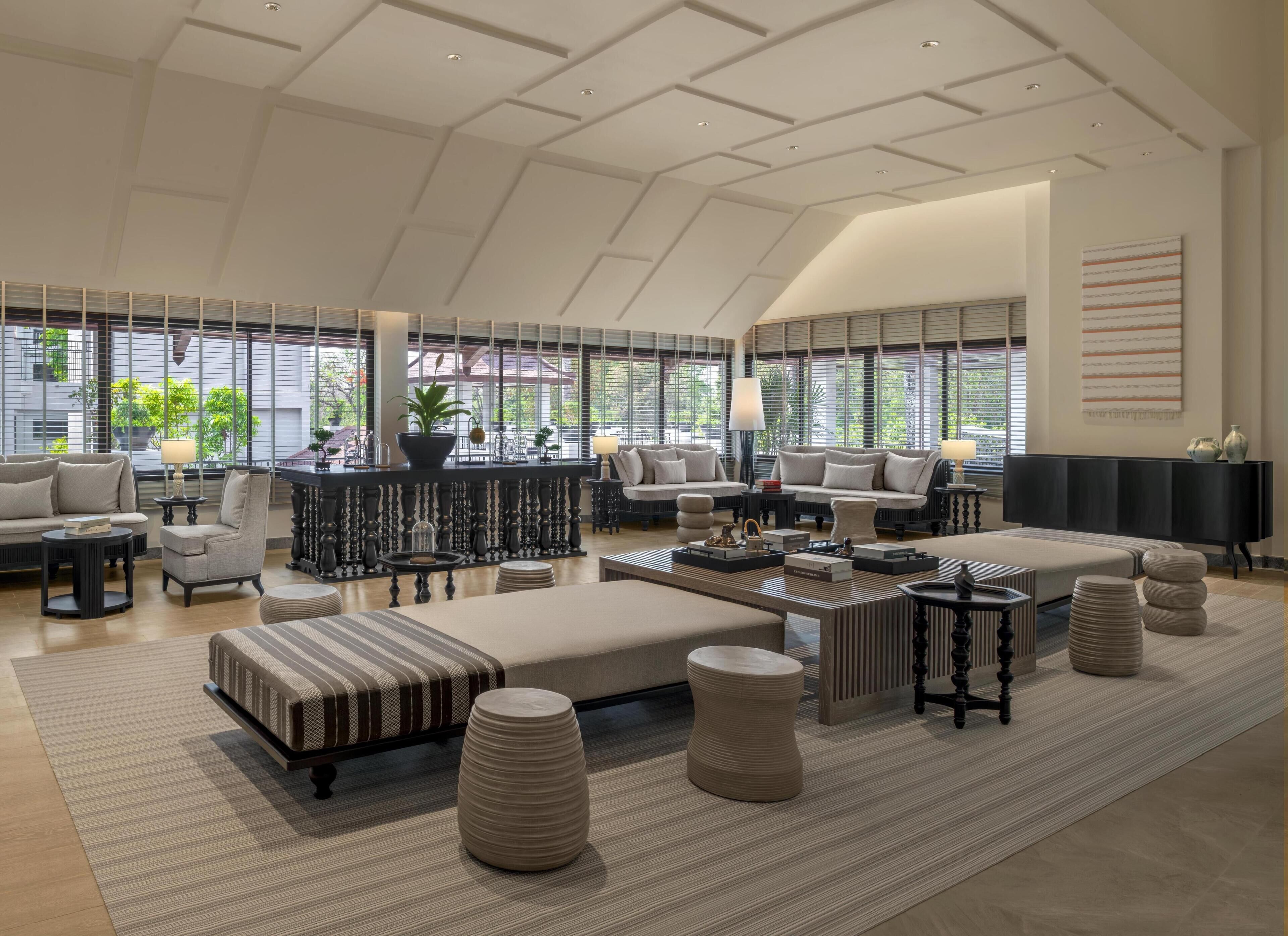 A spacious living room with a high ceiling, large windows, and a modern design.