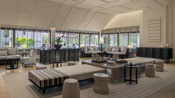 A spacious living room with a high ceiling, large windows, and a modern design.