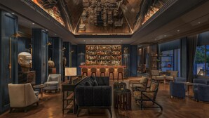 A spacious lounge with a bar, plush seating, and a large window offering a view. - Kahavadi Chiang Rai, Curio Collection By Hilton (Chiang Rai)