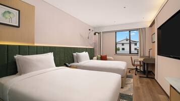 A hotel room with two beds, a desk, a chair, and a large window.