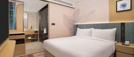 A modern hotel room with a large bed, a bedside table with a phone, a mirror, a wardrobe, and a bathroom visible through an open door.