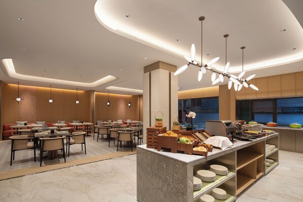 A modern dining area with a buffet setup, multiple seating arrangements, and contemporary lighting fixtures. - Hilton Garden Inn Shaoxing Lu Xun Native Place (Shaoxing)