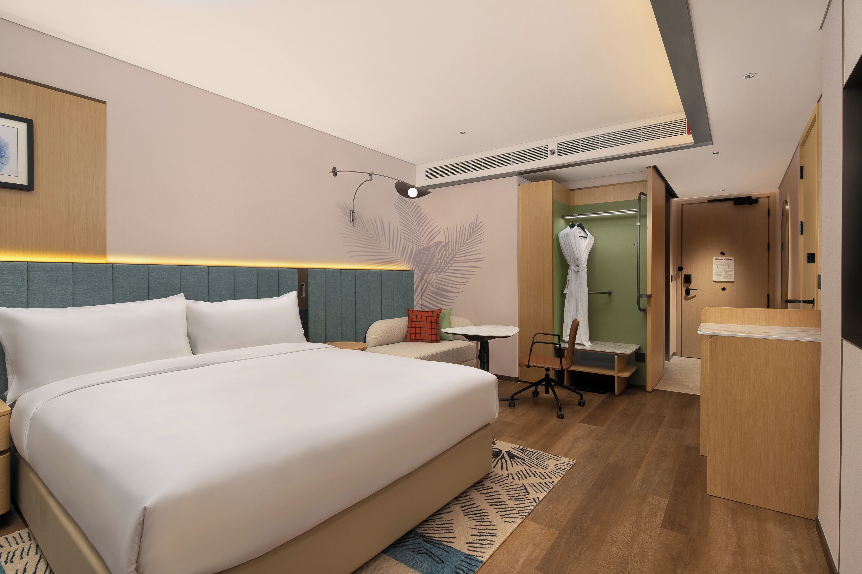Habitación de hotel moderna con una cama grande, un escritorio pequeño, una silla, una mesa y zona de ducha.
