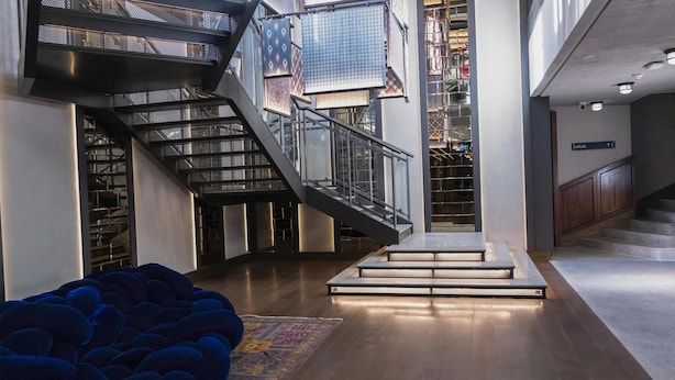A spacious interior with a modern staircase, a blue bean bag chair, and a patterned rug. - Canopy By Hilton Istanbul Taksim (Istanbul)