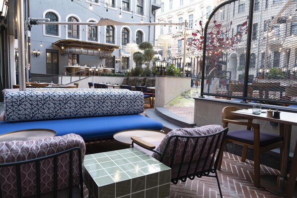 An outdoor seating area with a patterned sofa, chairs, and a small table. - Canopy By Hilton Istanbul Taksim (Istanbul)