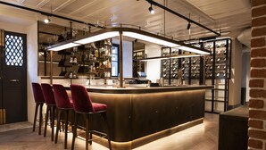 A bar area with a curved counter, red bar stools, and a wine rack in the background. - Canopy By Hilton Istanbul Taksim (Istanbul)