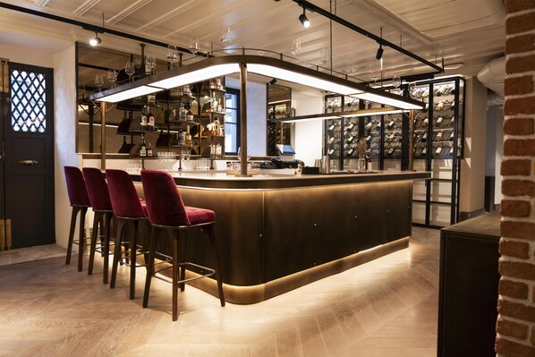 A bar area with a curved counter, red bar stools, and a wine rack in the background. - Canopy By Hilton Istanbul Taksim (Istanbul)