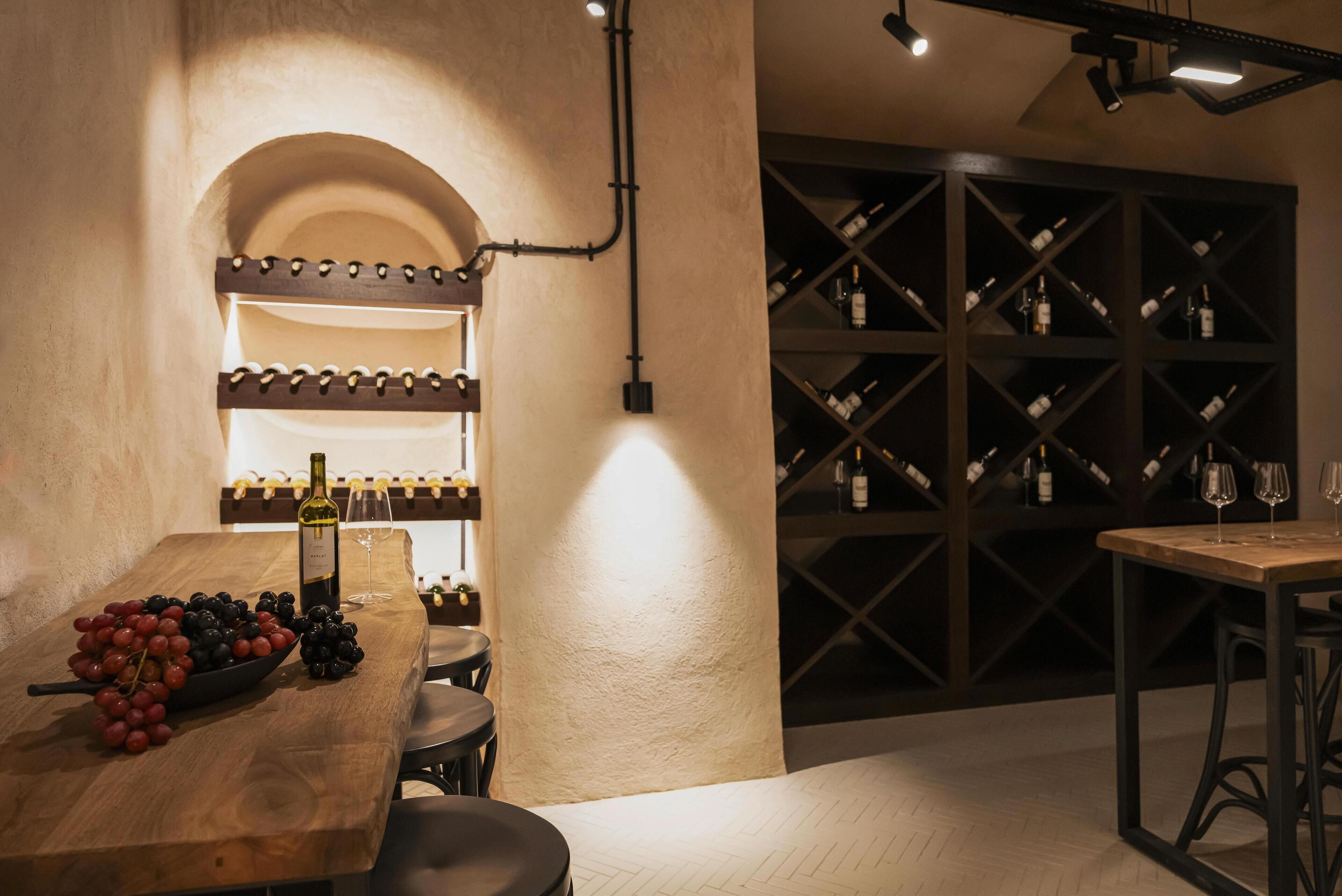 A wine cellar with wooden tables, a wine rack, and a bottle of wine.